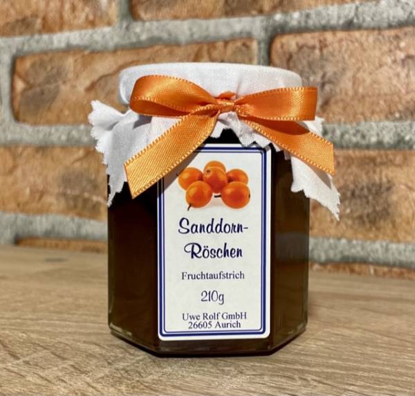 Glas Sanddornröschen Fruchtaufstrich 210 g mit orangefarbener Schleife vor Backsteinwand